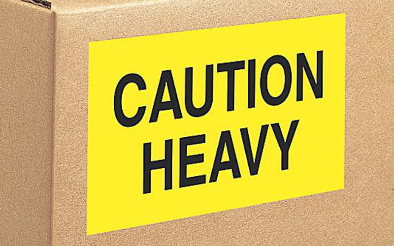 Hi-vis yellow CAUTION HEAVY label on a shipping carton